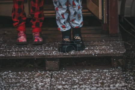 Téléchargez les photos : Photo recadrée des jambes des enfants célébrant Noël et le Nouvel An saison des vacances d'hiver en plein air attente Père Noël. - en image libre de droit
