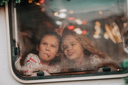 Foto de Niños celebrando Navidad y Año Nuevo temporada de vacaciones de invierno esperando a Santa Claus en autocaravana. Los niños que pasan tiempo juntos tomando algo de leche disfrutan del bastón de caramelo y las galletas en el remolque de la caravana de Navidad - Imagen libre de derechos