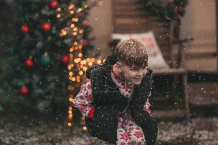 Photo for Little boy celebrating Christmas and New Year winter holidays season outdoor, waiting Santa near Xmas camper trailer and rejoices at first snow enjoying childhood - Royalty Free Image