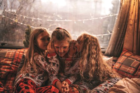 Photo for Children celebrating Christmas and New Year winter holidays season in camper. Little girls joyful spending time together grimace whispering secrets in ear at Xmas camper trailer enjoying childhood - Royalty Free Image