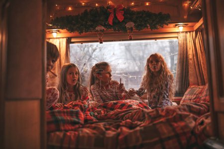 Téléchargez les photos : Enfants célébrant Noël et Nouvel An saison des vacances d'hiver en camping-car. Les enfants actifs passent du temps ensemble grimace avoir du plaisir et lire le livre à Noël caravane camping-car profiter de l'enfance - en image libre de droit