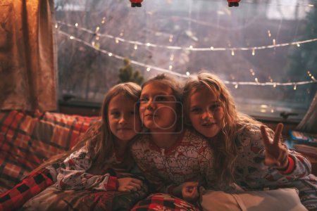 Téléchargez les photos : Enfants célébrant Noël et Nouvel An saison des vacances d'hiver en camping-car. Petites filles joyeuses passer du temps ensemble grimace chuchotant secrets dans l'oreille à caravane de camping-car de Noël profiter de l'enfance - en image libre de droit