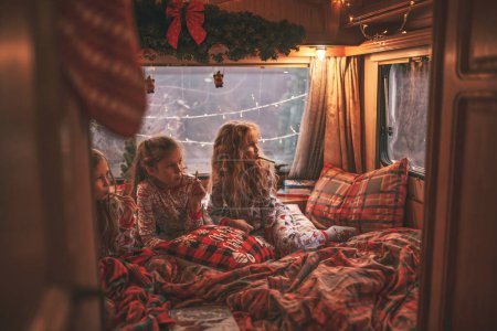 Téléchargez les photos : Les enfants qui célèbrent Noël et le Nouvel An saison des vacances d'hiver attendent le Père Noël en camping-car. Les enfants passant du temps ensemble grimace boire du lait profiter de la canne à bonbons et des biscuits à la caravane de Noël - en image libre de droit
