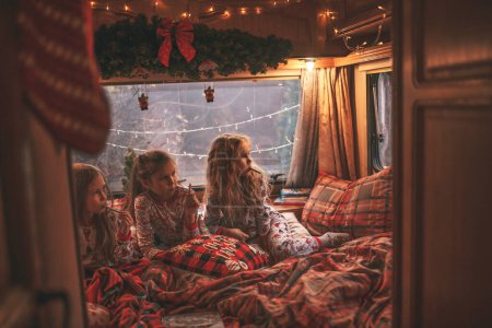 Photo for Children celebrating Christmas and New Year winter holidays season waiting Santa in camper. Kids spending time together grimace having drinks milk enjoy candy cane and cookies at Xmas camper trailer - Royalty Free Image