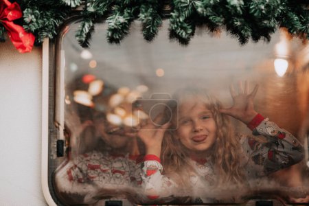 Photo for Children celebrating Christmas and New Year winter holidays season waiting Santa in camper. Kids spending time together grimace having drinks milk enjoy candy cane and cookies at Xmas camper trailer - Royalty Free Image