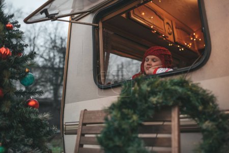 Photo for Girl celebrating Christmas and New Year winter holidays season waiting Santa at Xmas camper trailer. - Royalty Free Image