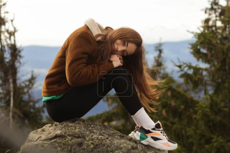 Photo for Girl with red hair, young student girl, fan of twilight, forest American student, cool colorfully sneakers, velvet.Attractive lady with red hair and fluffy jacket, traveling outdoor on the mountains, long socks, colourful sneakers, Swiss alps. - Royalty Free Image
