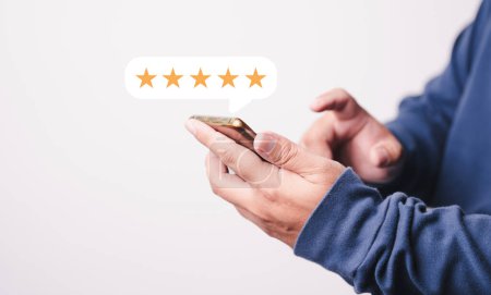 Photo for Customer Man hand press on smartphone screen with golden five star reviews and excellent press level for best rating in review. - Royalty Free Image