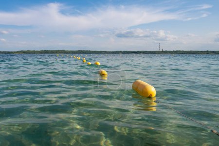 Téléchargez les photos : Ligne de bouée jaune flottant sur l'eau tranquille. Zone de baignade de sécurité - en image libre de droit