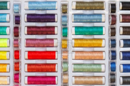 Foto de Un conjunto de hilos de colores y bobinas de plástico para máquinas de coser. Industria textil - Imagen libre de derechos