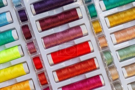 Foto de Vista plana de los hilos de arco iris y bobinas de plástico para máquinas de coser - Imagen libre de derechos