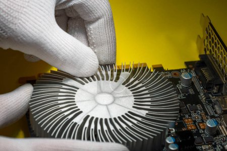 A technician in white antistatic gloves assembling cooling radiator onto the computer graphic card
