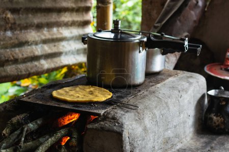 traditional cooking on a Colombian farm, with an arepa roasting next to a pressure cooker on a handmade brick stove covered with gray ash.