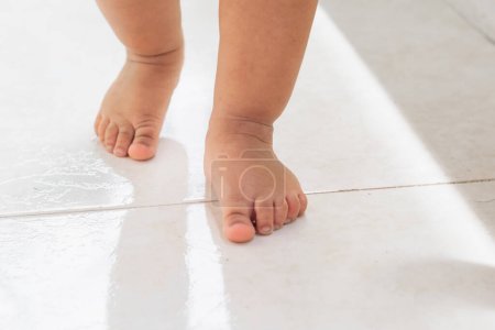 Téléchargez les photos : Gros plan des pieds d'une petite fille latine faisant ses premiers pas, debout sur un fond blanc - en image libre de droit