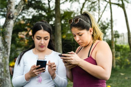 Photo for Friends in the park, very focused on looking at their cell phones. concept of technology - Royalty Free Image