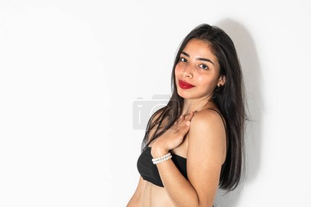 Photo for Close-up portrait of a beautiful Latina teenager, posing sideways with one hand on her chest. - Royalty Free Image