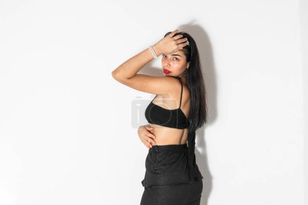 Photo for Portrait of young latina woman with brown skin posing with her back to the camera while looking at it - Royalty Free Image