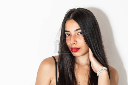 Photo for Close-up portrait of a beautiful young latina woman with a hand on her cheek looking straight ahead. - Royalty Free Image