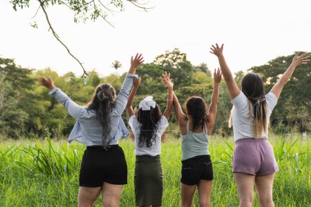 Photo for Four Latin girls celebrating, raising their hands to the sky, symbol of freedom and joy above - Royalty Free Image