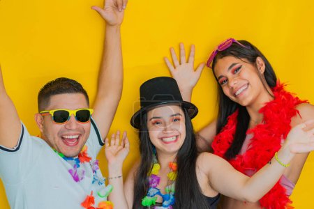 three young latinos, celebrating very happily while raising their hands. yellow background
