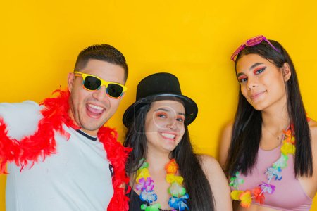 three multiethnic young people, dressed for the party or carnival, smiling on a yellow background