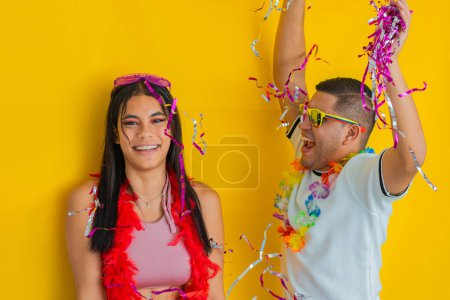 young latin man celebrating with his hands up next to a brunette woman. carnival concept.