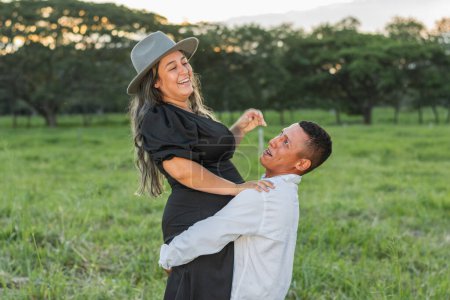 Photo for Brown dark-haired latin man straining hard to lift his girlfriend while she smiles with laughter - Royalty Free Image