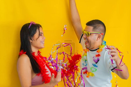 two young latinos celebrating, smiling and throwing colored streamers. carnival concept.