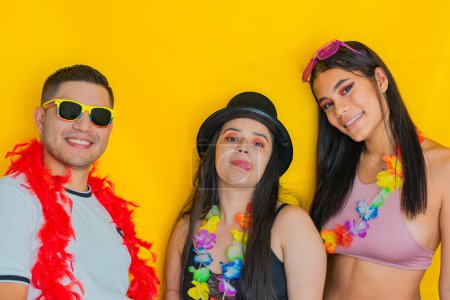 three young multiethnic, very happy young people in carnival clothes on a yellow background, smiling