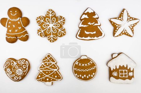 Téléchargez les photos : Pain d'épice de Noël sous la forme d'une maison, arbre de Noël, coeur, flocon de neige, étoile, boule de Noël et pain d'épice homme sur un fond blanc. Vue d'en haut - en image libre de droit
