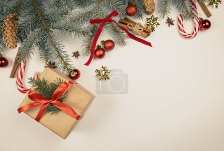 Foto de Fondo de Navidad para la tarjeta de felicitación. Ramas de árbol de Navidad con efecto nieve con cinta roja festiva, conos de pino, cajas de regalo y velas, sobre fondo de mármol blanco, espacio para copiar - Imagen libre de derechos