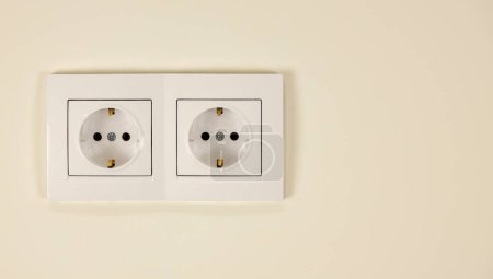 Téléchargez les photos : Doubles douilles blanches sur le mur. Le concept de fourniture d'électricité dans la maison - en image libre de droit