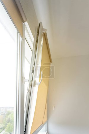 An open plastic window in an apartment, beige blinds. Curtain design concept