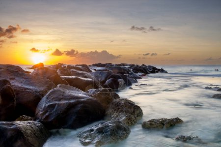 Foto de Atardecer tranquilo con grandes piedras entrando en el mar - Imagen libre de derechos