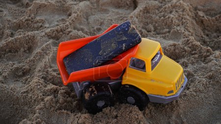 Téléchargez les photos : A phone on top of a toy car on the beach - en image libre de droit