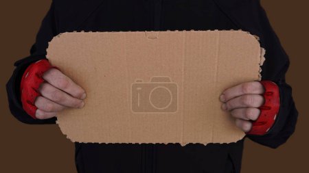 Téléchargez les photos : Une femme en gants rouges, tient un morceau de carton dans ses mains, comme un signe sur lequel vous pouvez écrire quelque chose - en image libre de droit