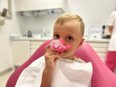 Un niño está probando una máscara de sedación con óxido nitroso, en el consultorio de un dentista