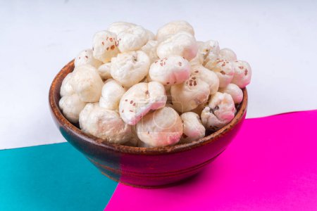 Téléchargez les photos : Lotus croustillant biologique éclate graines ou makhana phool dans un bol sur fond coloré - en image libre de droit