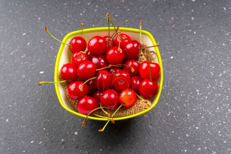 Foto de Tazón de cerezas rojas maduras frescas sobre fondo de granito - Imagen libre de derechos