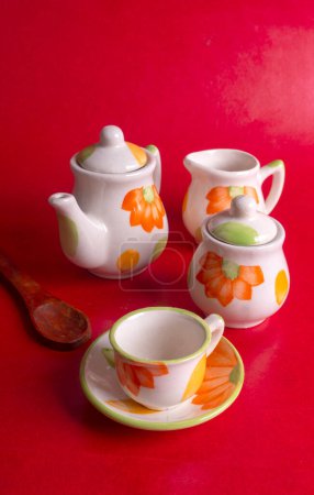 Photo for Ceramic cups with kettle on red colored background - Royalty Free Image