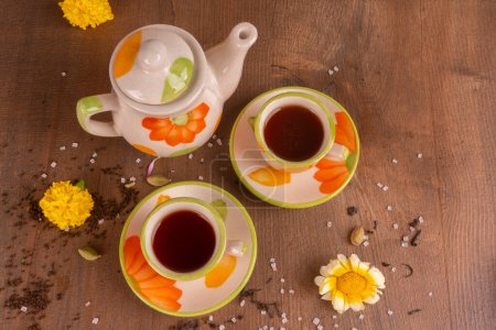 Photo for Indian masala tea in cups with kettle and spices on wooden background - Royalty Free Image