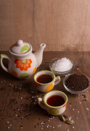 Photo for Indian masala tea in cups with kettle and spices on wooden background - Royalty Free Image