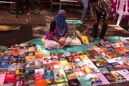 Téléchargez les photos : Femme vendant des livres dans la rue dans la ville indienne - en image libre de droit