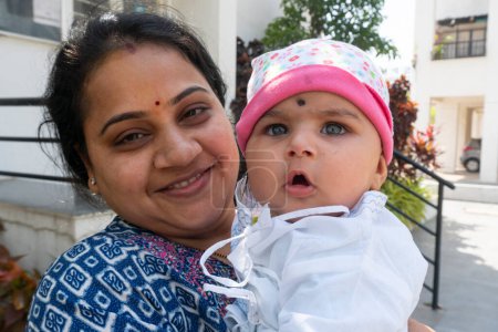 Téléchargez les photos : Pune, Maharashtra, Inde - 18 Mars, 2022 : Femme indienne avec un enfant mignon dans les mains célébrant le festival holi, peinture de couleur sur les visages - en image libre de droit