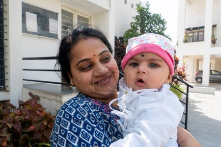 Téléchargez les photos : Pune, Maharashtra, Inde - 18 Mars, 2022 : Femme indienne avec un enfant mignon dans les mains célébrant le festival holi, peinture de couleur sur les visages - en image libre de droit