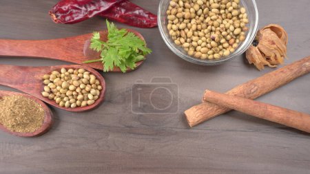 Foto de Semillas de cilantro seco con cucharas de bambú pequeñas y hojas de cilantro frescas verdes, ingredientes de especias famosas en la cocina de Asia. - Imagen libre de derechos