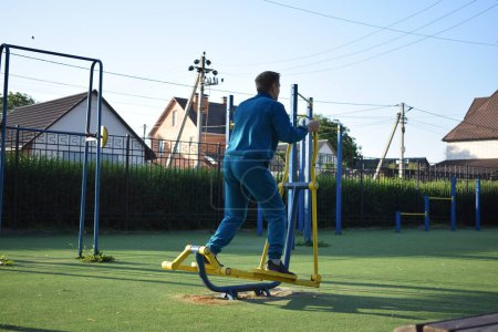 A dedicated young athlete puts in the hard work, vigorously training on gym equipment outdoors to prepare his body. He builds strength and endurance before hitting the field or court for competition