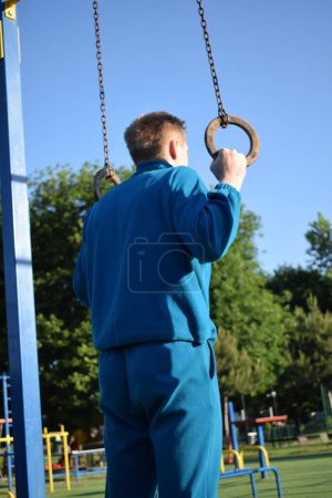 A dedicated young athlete puts in the hard work, vigorously training on gym equipment outdoors to prepare his body. He builds strength and endurance before hitting the field or court for competition