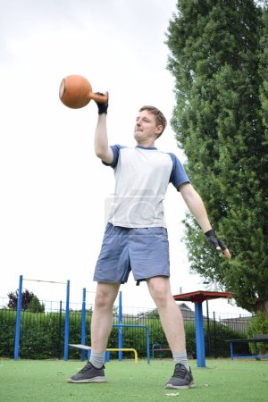 Photo for A young man in sportswear engages in a workout, using a sport tool for physical exercises on a sports field in the morning. His dedication to fitness performs training routine with focus and energy - Royalty Free Image