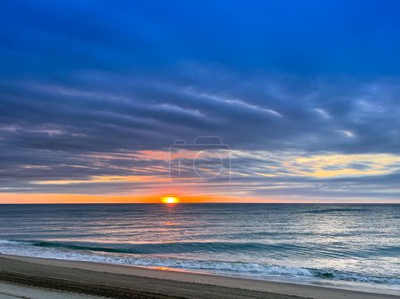 Puesta de sol sobre un fondo nublado en la playa de Canet en Rosellón